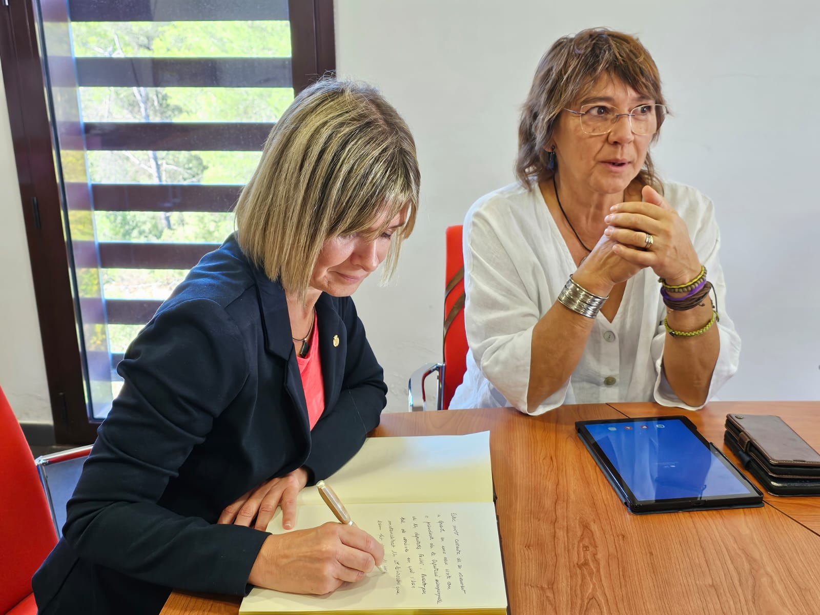 La presidenta Noemí Llauradó, signant el llibre d'honor al costat de l'alcaldessa, Roser Bruzón 